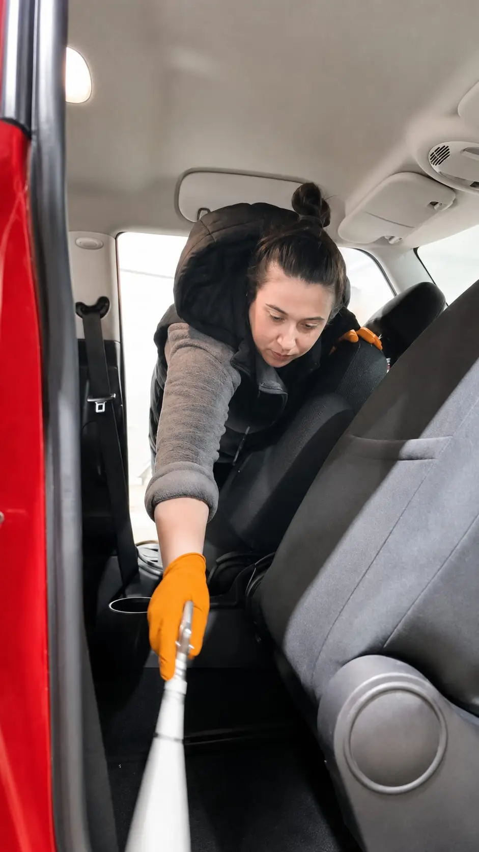 Aspirado del suelo trasero de un coche durante la limpieza interior